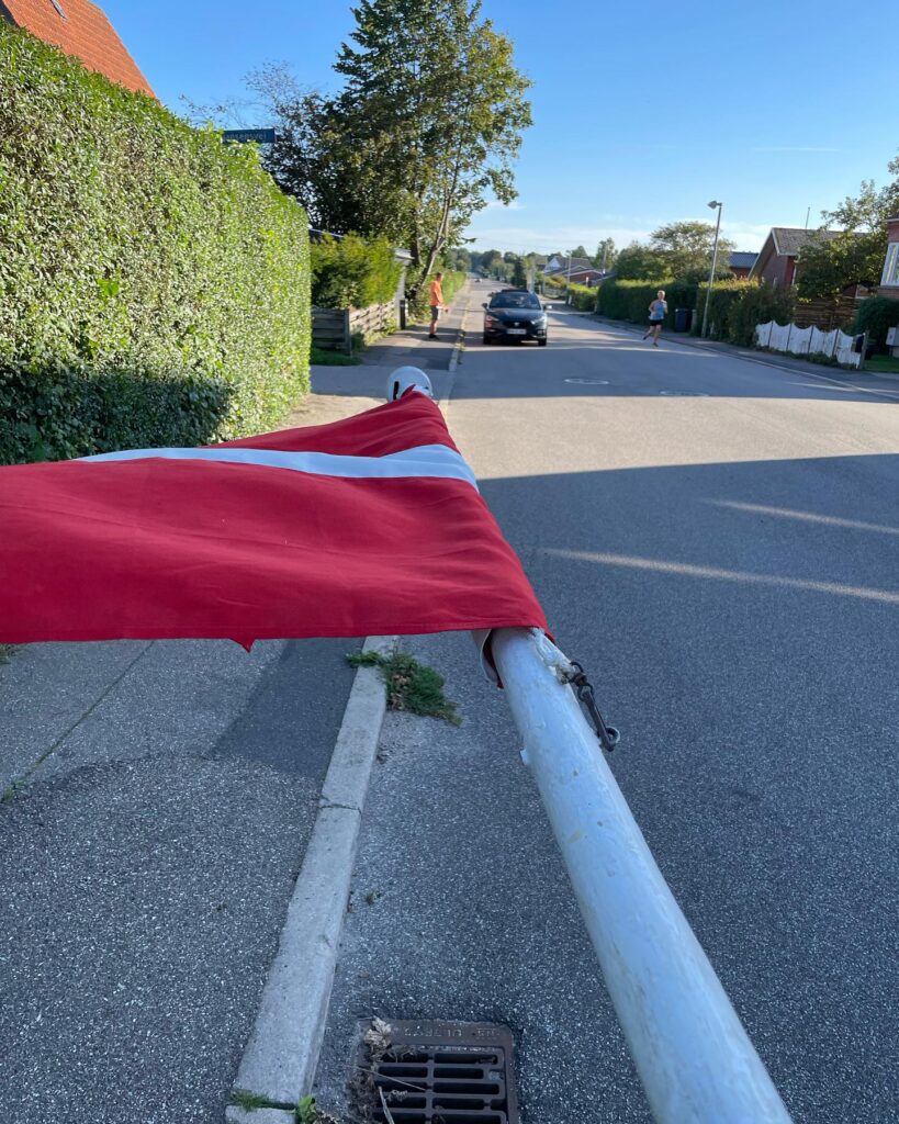 Dannebrog på flagsatng der ligger vandret og flaget er ved at blive rullet sammen